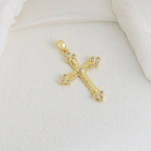 Detailed view of a gold cross pendant with fine texture and cubic zirconia stones