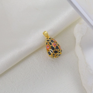 Detail of egg-shaped pendant with gold frame and red black enamel on silk background