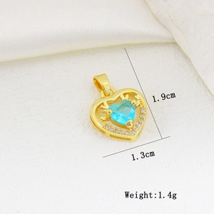 Macro view of gold-plated heart pendant with blue gemstone and white zircon accents