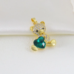 Macro shot of a golden bear pendant with a green heart crystal and micro-pave zircons