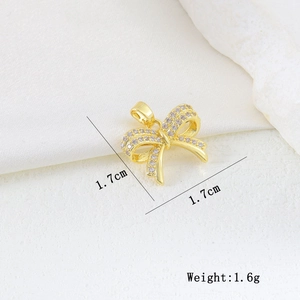 Macro shot of 1.7cm gold butterfly pendant with cubic zirconia on white silk background