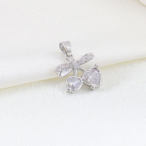 Macro detail of silver bow pendant with cherry-shaped heart cubic zirconia stones