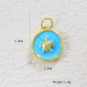 Macro view of 18K gold plated turtle charm with blue enamel on stone background