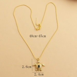 Detail view of a gold turtle pendant necklace featuring a black gem and dimensions