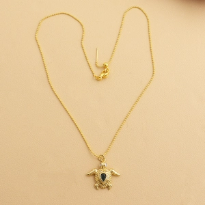 Detailed view of turtle pendant with black gemstone and gold-plated adjustable bead chain