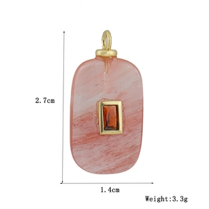 Detail of pink marble pendant with orange gemstone and gold frame measuring 2.7cm