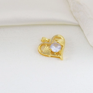Macro view of heart-shaped gold pendant with central zircon and pavé wing details