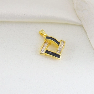 Macro view of geometric gold pendant with black enamel and baguette zircon inlay