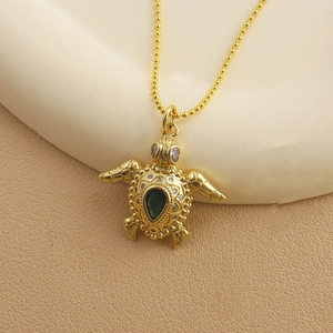 Detailed macro view of golden turtle pendant necklace with green drop gemstone
