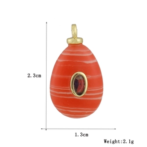 Detail view of orange oval gemstone pendant with purple stone inlay and gold hook