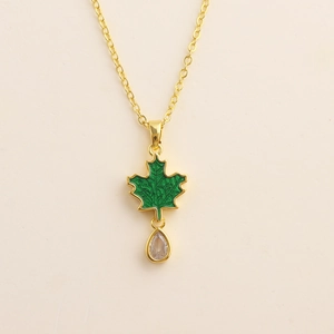 Detail of gold necklace with green enamel maple leaf pendant and teardrop zircon