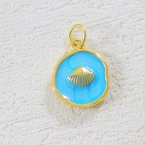 Detail of 18K gold shell pendant with blue enamel on a rustic white background
