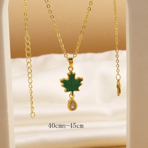 Detail view of 40-45cm gold maple leaf necklace with green enamel and teardrop crystal