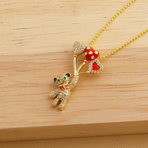 Detailed macro view of a crystal teddy bear pendant with balloons on a golden bead chain