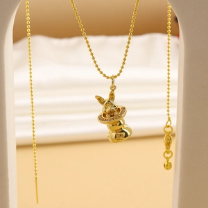 Close-up of golden bunny in magic hat pendant with sparkling zircons and round bead chain