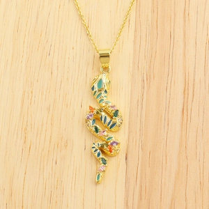 Close-up of golden snake pendant with colorful crystals on light wood background