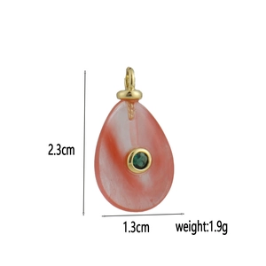 Dettaglio del ciondolo a goccia rossa con pietra verde e gancio dorato, altezza di 2,3 cm