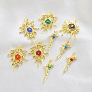 Detailed macro of golden Evil Eye charms in flame and tusk shapes for DIY jewelry making
