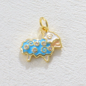 Dettaglio macro del ciondolo a forma di pecora in smalto blu, finitura oro e cristalli
