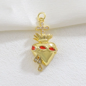 Detalle de un colgante de corazón sagrado bañado en oro 18k con esmalte rojo y cristales