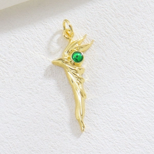Macro shot of gold bird pendant with detailed feathers and a vibrant green gemstone