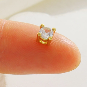 Gros plan d'une petite perle en cuivre doré sertie de zircons sur le bout d'un doigt