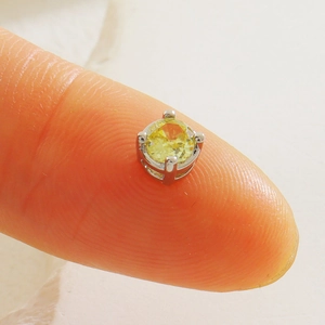 Mini puce d'oreille en cristal jaune taillé avec griffe en argent sur le bout du doigt