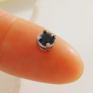 Détail macro d'une perle de zircon noir rond de 4mm sertie sur métal argenté à 4 griffes