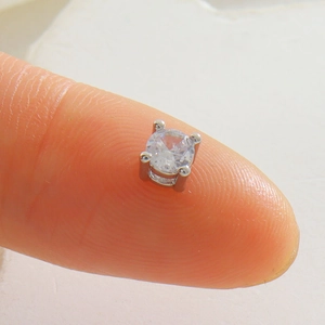 Vue macro d'une perle intercalaire en zircon carré sur le bout du doigt pour comparer la taille