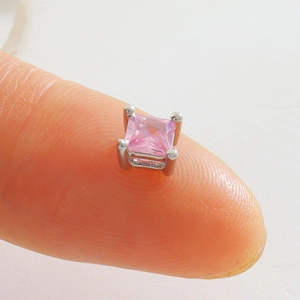 Gros plan d'un clou d'oreille avec pierre rose carrée et monture argentée à quatre griffes
