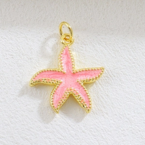 Detailed view of a golden starfish charm with pink glitter enamel and beaded edges