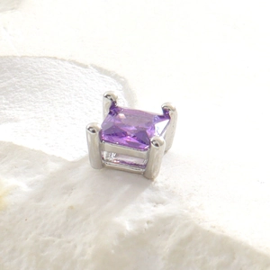 Gros plan d'une pierre précieuse violette carrée sur une monture argentée à quatre griffes