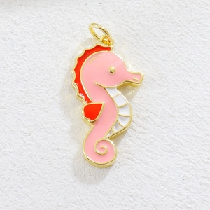 Close-up of a pink and red enamel seahorse charm pendant with gold-plated edges and ring