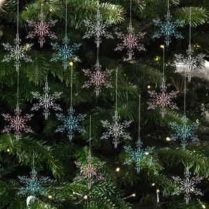 Set of clear pink and blue acrylic snowflake ornaments hanging on a Christmas tree