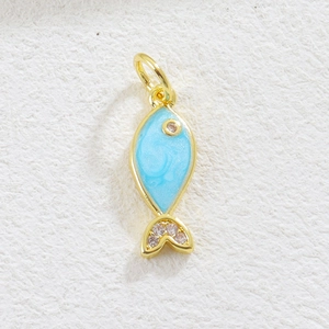 Detailed macro view of a golden fish pendant with light blue enamel and zircon stones