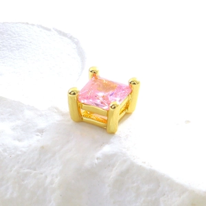 Gros plan d'une perle en cristal rose sertie sur un support en cuivre plaqué or à griffes
