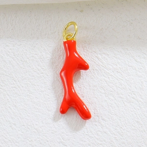 Detail of a bright red coral branch pendant with a gold ring for DIY jewelry making