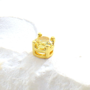 Détail macro d'une puce d'oreille en cuivre doré sertie d'un cristal rond jaune brillant
