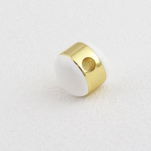 Detalle macro de una cuenta espaciadora de oro de 18k con cerámica blanca para joyas DIY