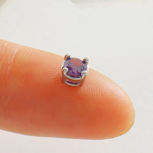 Macro d'une petite boucle d'oreille en zircon violet avec monture argentée à quatre griffes