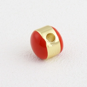 Vista macro detallada de una cuenta redonda bañada en oro con esmalte rojo para joyas