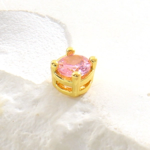 Macro d'une pierre rose ronde sertie sur quatre griffes dorées pour la création de bijoux