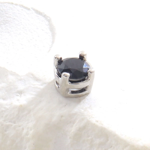Détail macro d'une perle en zircon noir rond avec serti à quatre griffes et découpes en H