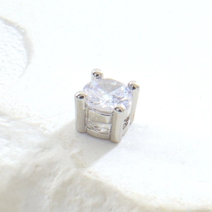 Détail macro d'un zircon rond serti dans une monture carrée à quatre griffes en argent