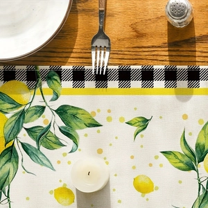 Detail of lemon pattern table runner with black and white plaid border on wood table