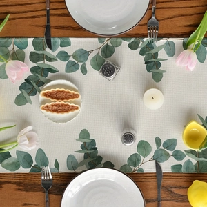 Detailed top view of eucalyptus leaf table runner on a dark wood dining table setup