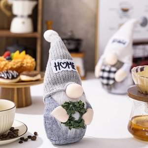 Detailed view of a Christmas gnome doll with Home embroidery and festive mini wreath