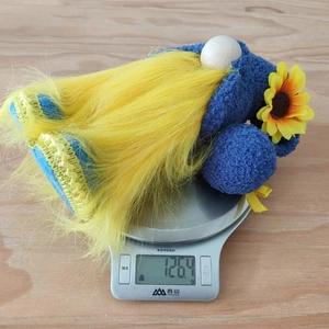 Detailed view of handmade spring sunflower gnome weighing 126.4g on a kitchen scale