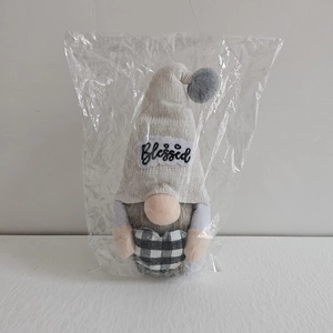 Detail of Christmas gnome plush doll wearing a grey Blessed hat holding a buffalo plaid heart