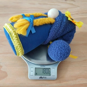 Weight measurement of a blue plush sunflower gnome gnome with yellow braids on a scale